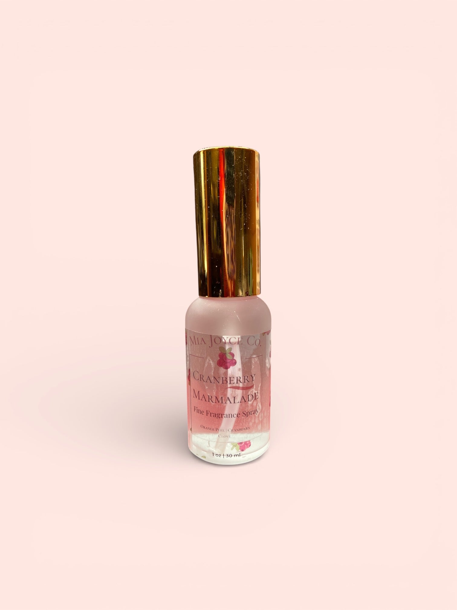 Perfume bottle with gold cap on a light pink background