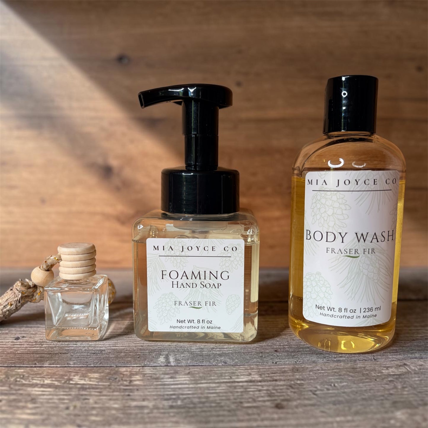 Three bottles of Mia Joyce Co. products on a wooden surface with a wooden background.