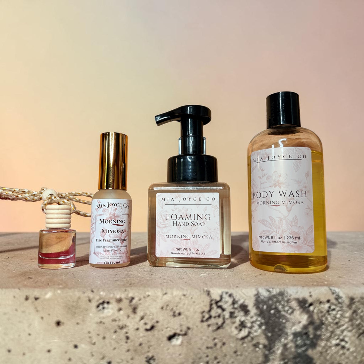 Set of Mia Joyce Co. skincare products on a textured surface with a gradient background